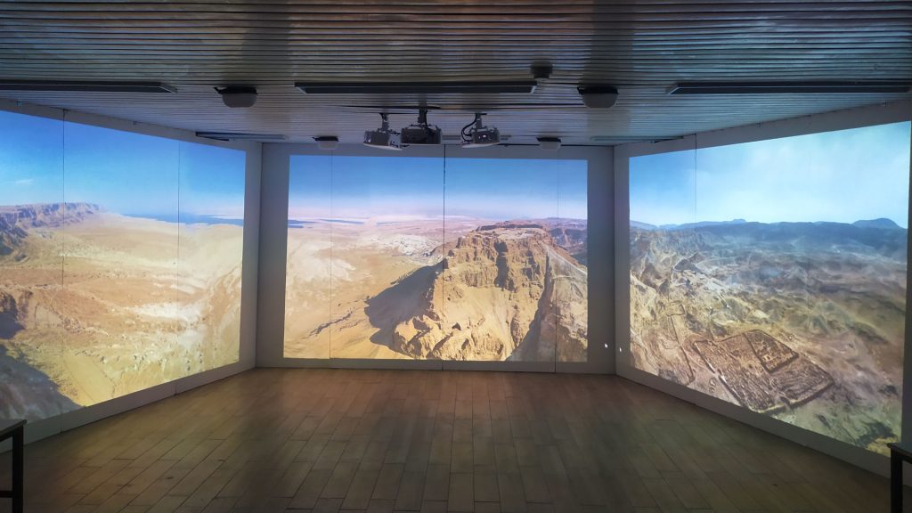 תצלום של החדר האימרסיבי, עם פנורמה אווירית של מצדה והמדבר שסביבה המוקרנת ברצף על שלושת קירות ההקרנה